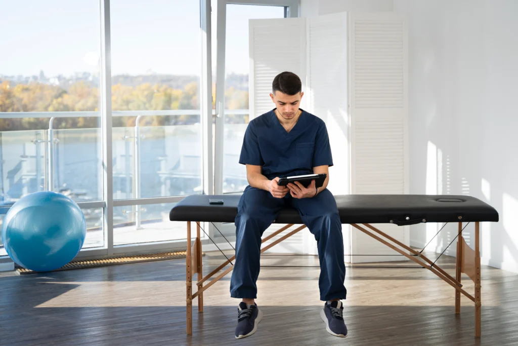 Fisioterapeuta masculino usando tableta en clínica de fisioterapia.