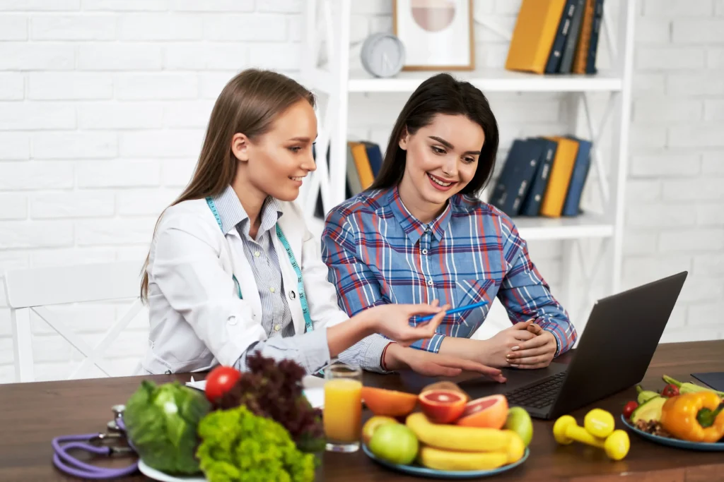 Médica y paciente revisan plan de alimentación saludable en laptop.