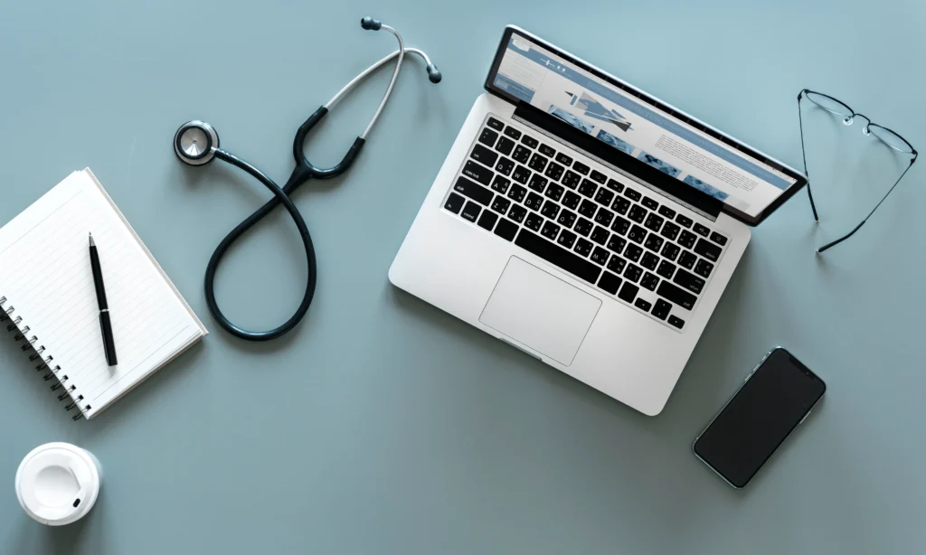 Equipo médico con laptop y estetoscopio sobre escritorio.