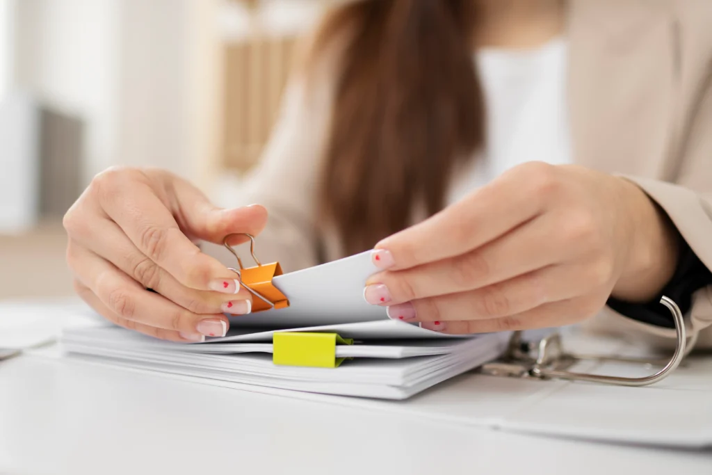 Mujer organizando documentos en carpeta con etiquetas.