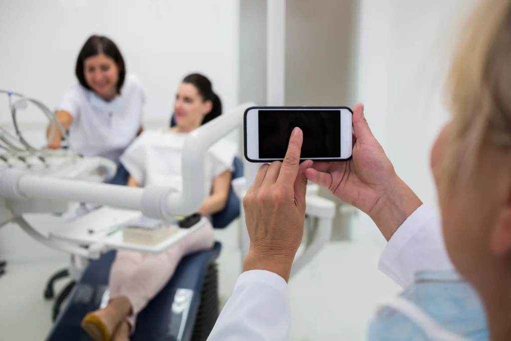 Médico tomando foto con teléfono en consulta dental.