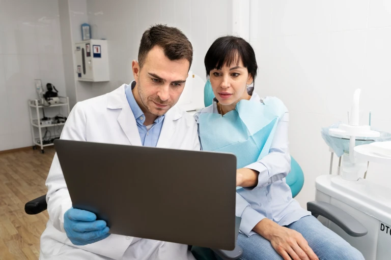 Dos profesionales de una clínica dental revisando información en un portátil