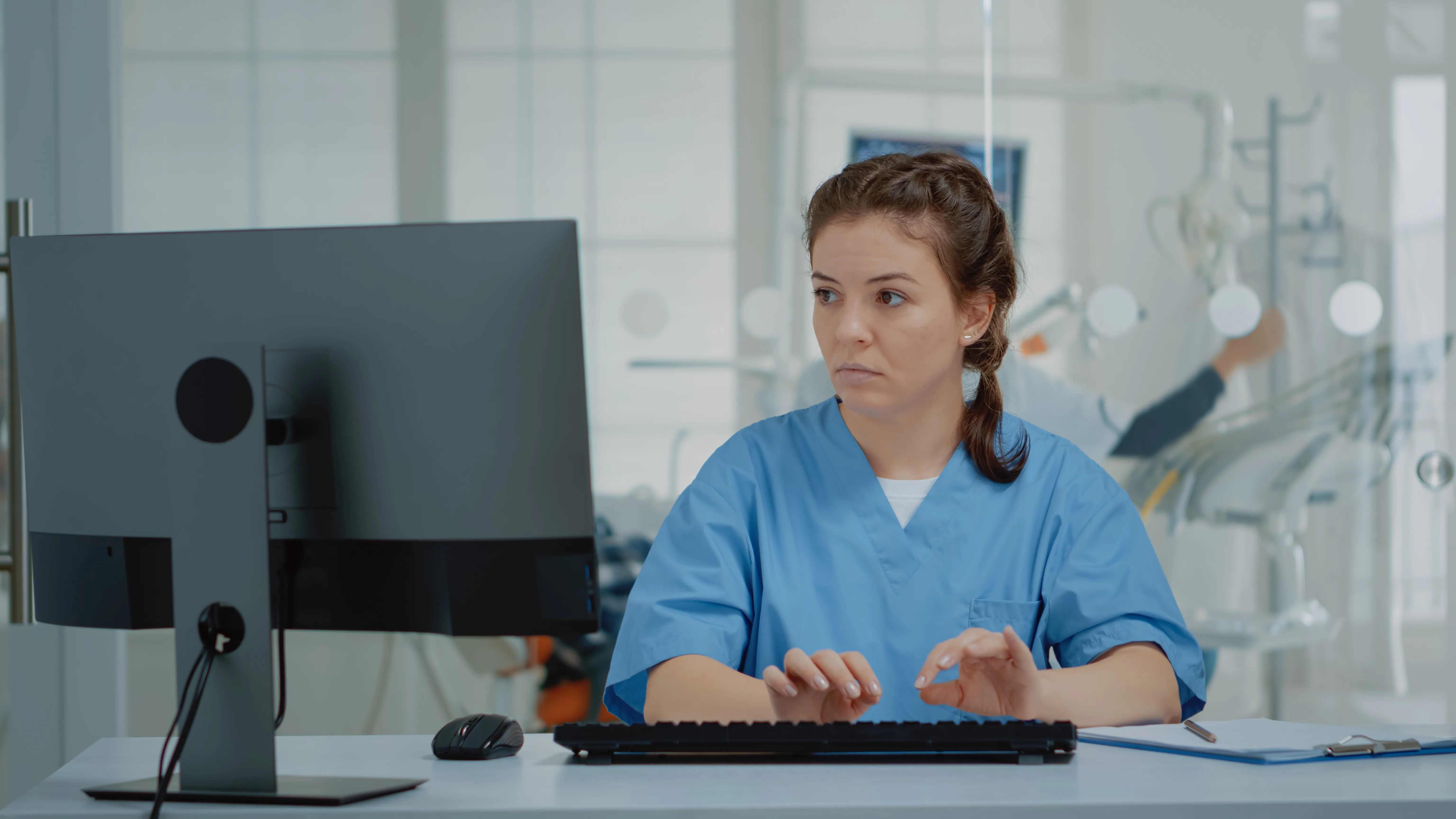 Podólogo trabajando en su consultorio con software de gestión clínica en pantalla